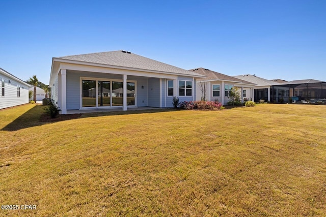 rear view of house featuring a yard and a shingled roof