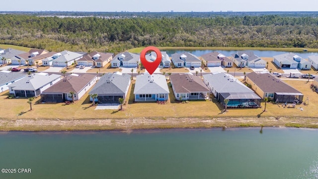 drone / aerial view featuring a forest view, a residential view, and a water view