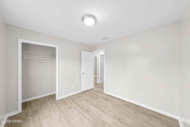 unfurnished bedroom featuring baseboards, visible vents, a closet, and wood finished floors