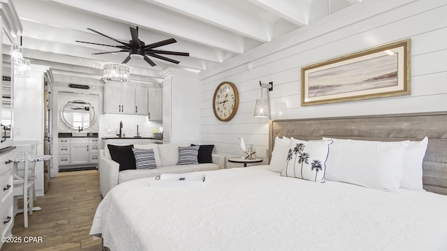 bedroom with wood finished floors, beamed ceiling, and a sink