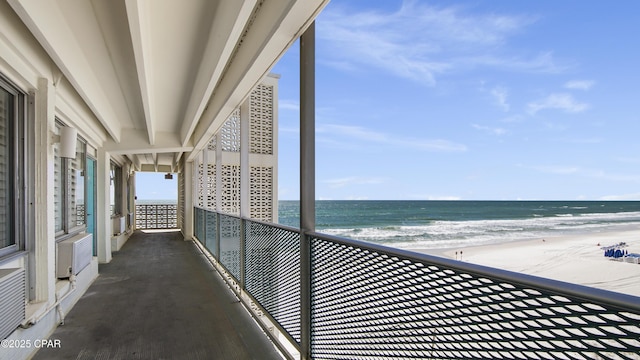 balcony with a beach view, a wall unit AC, and a water view