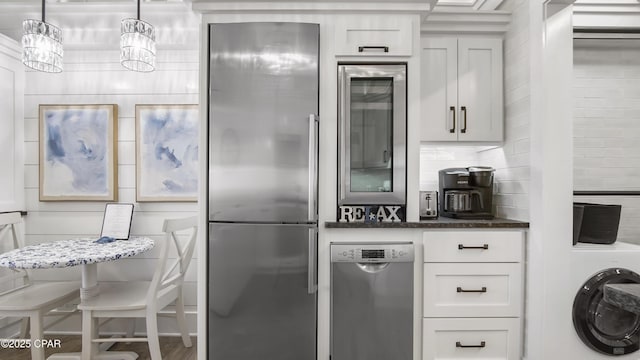 kitchen with white cabinets, stainless steel fridge, dark stone countertops, and washer / dryer
