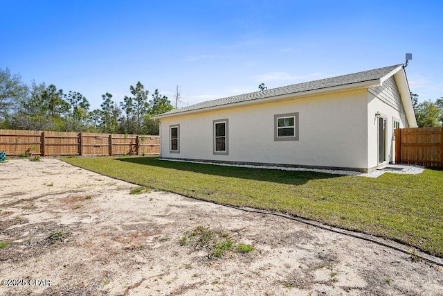 back of house featuring a yard, a fenced backyard, and stucco siding
