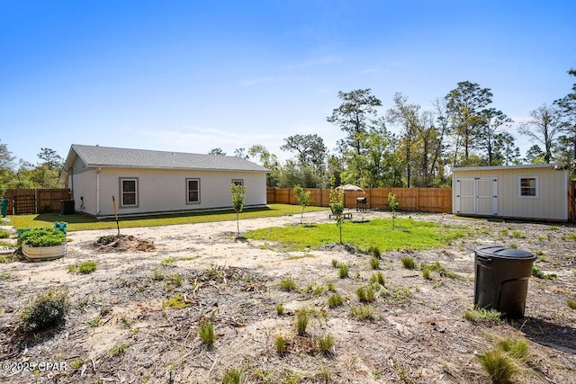view of yard featuring an outbuilding, a fenced backyard, cooling unit, and a storage unit