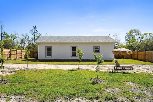 rear view of house featuring a yard and a fenced backyard