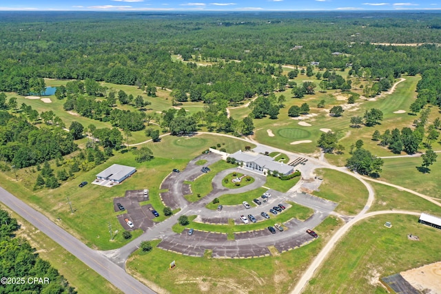birds eye view of property with a wooded view, view of golf course, and a water view