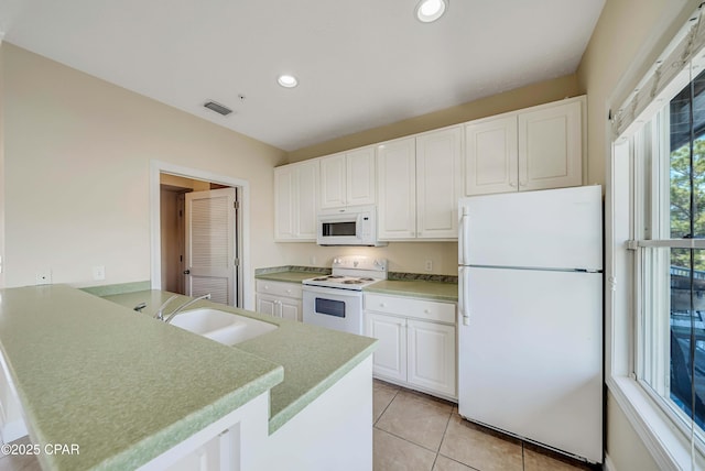 kitchen with a sink, white appliances, white cabinets, a peninsula, and visible vents