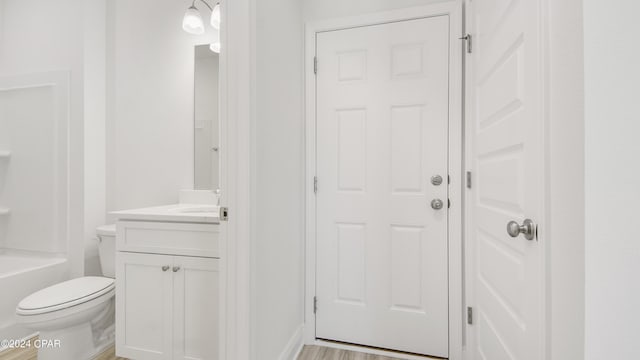 full bath with vanity, toilet, and a tub to relax in