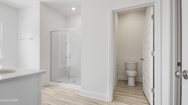 full bathroom featuring baseboards, a stall shower, toilet, and wood finished floors
