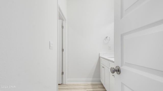 bathroom with baseboards, wood finished floors, and vanity