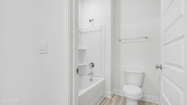 full bath featuring shower / bathtub combination, toilet, baseboards, and wood finished floors
