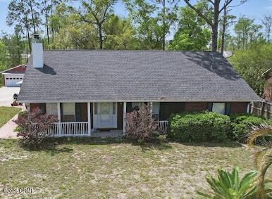 4435 Mill Bayou Rd, Panama City, FL 32404 - ranch-style house with covered porch, a chimney, a front yard, and view of scattered trees