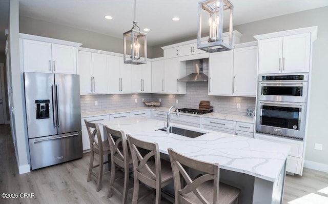 244 Sands St, Panama City Beach, FL 32413 - kitchen featuring stainless steel appliances, a sink, wall chimney range hood, light wood-style flooring, and white cabinets