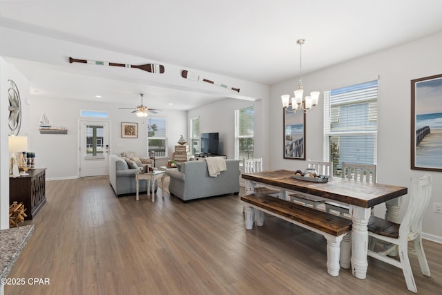 dining space with baseboards, wood finished floors, and ceiling fan with notable chandelier