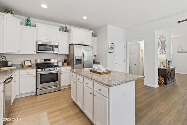 kitchen with recessed lighting, a center island, white cabinetry, light wood-style floors, and stainless steel appliances