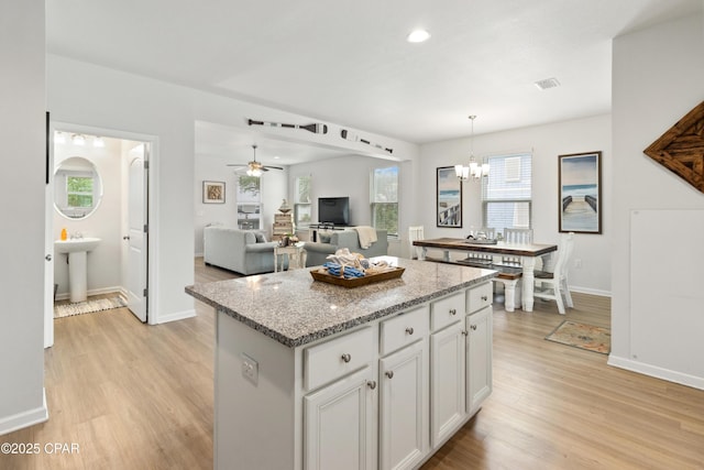 kitchen featuring visible vents, light wood finished floors, a kitchen island, and plenty of natural light