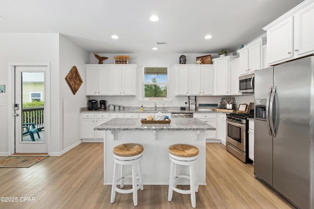 kitchen with a kitchen bar, light wood-style floors, a sink, and stainless steel appliances