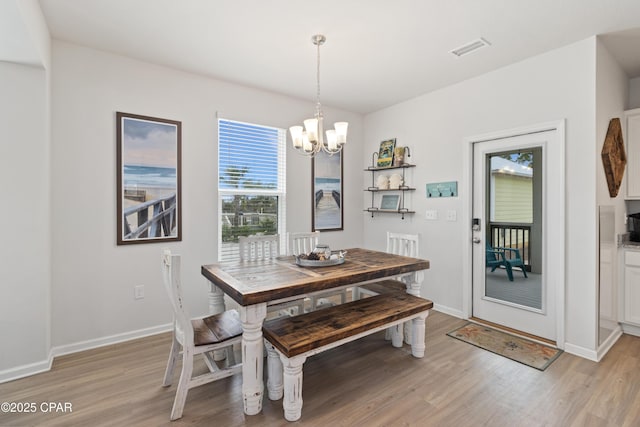 dining area featuring a chandelier, light wood finished floors, baseboards, and visible vents