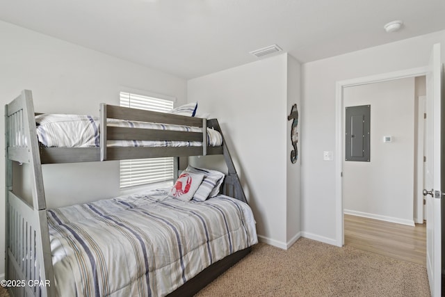 carpeted bedroom with visible vents, baseboards, and electric panel
