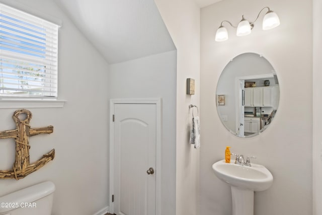bathroom featuring a sink, toilet, and lofted ceiling