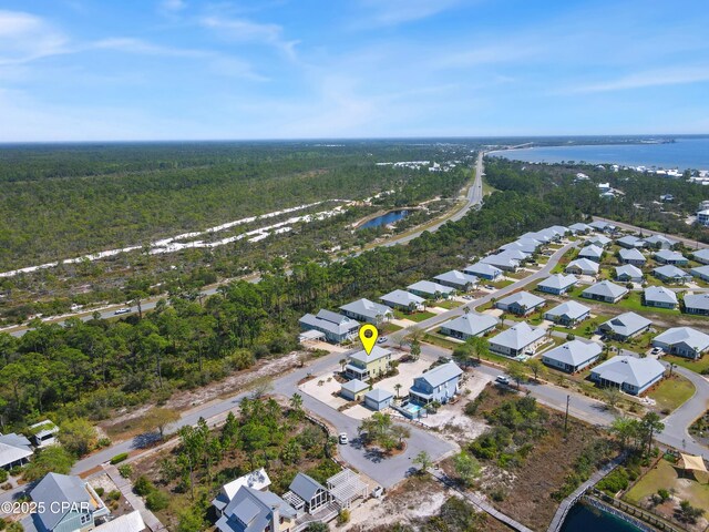 drone / aerial view with a forest view, a residential view, and a water view