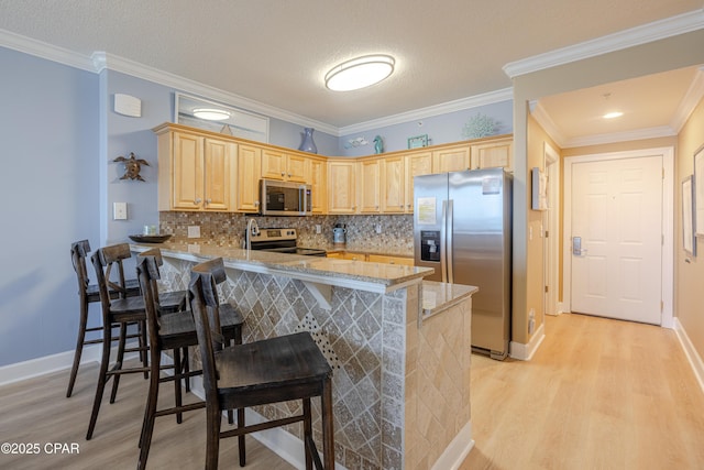 17643 Front Beach Rd Unit 1805, Panama City Beach, FL 32413 - kitchen with stainless steel appliances, light wood-type flooring, light brown cabinets, a peninsula, and crown molding