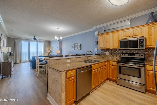 17643 Front Beach Rd Unit 1805, Panama City Beach, FL 32413 - kitchen with appliances with stainless steel finishes, ornamental molding, a sink, open floor plan, and light wood-style flooring