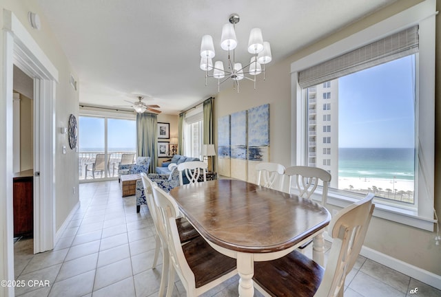 dining area with light tile patterned flooring, baseboards, a water view, and ceiling fan with notable chandelier
