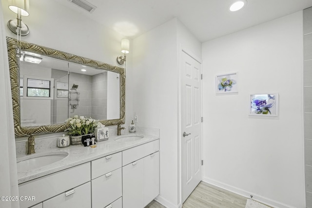7124 Leeward St, Port St Joe, FL 32456 - full bathroom with double vanity, wood finished floors, tiled shower, and baseboards