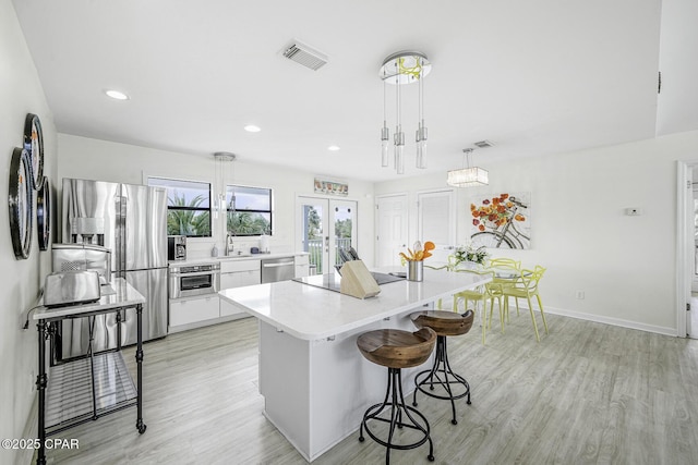 7124 Leeward St, Port St Joe, FL 32456 - kitchen featuring stainless steel appliances, a breakfast bar area, light wood-style floors, light countertops, and recessed lighting