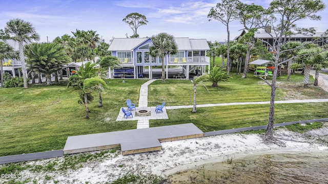 7124 Leeward St, Port St Joe, FL 32456 - view of front of property with a fire pit, a front lawn, a deck, and metal roof