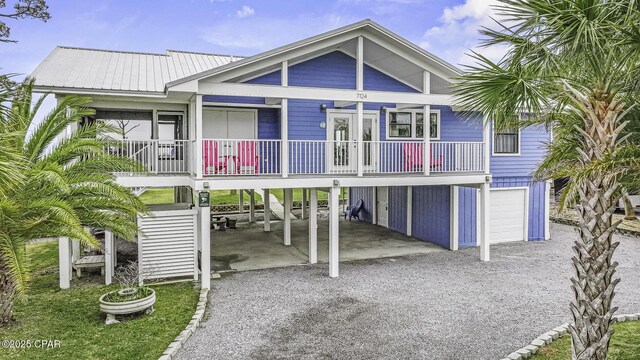 7124 Leeward St, Port St Joe, FL 32456 - view of front of property with a carport, gravel driveway, covered porch, french doors, and metal roof