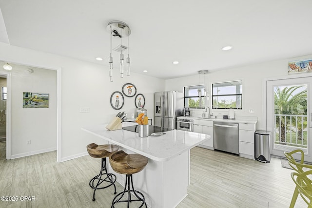 7124 Leeward St, Port St Joe, FL 32456 - kitchen with stainless steel appliances, a sink, a kitchen bar, light wood-type flooring, and white cabinetry