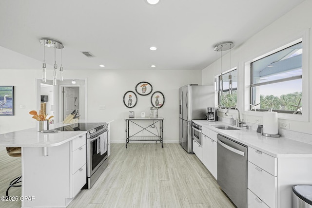 7124 Leeward St, Port St Joe, FL 32456 - kitchen with stainless steel appliances, a kitchen breakfast bar, white cabinets, decorative light fixtures, and a sink