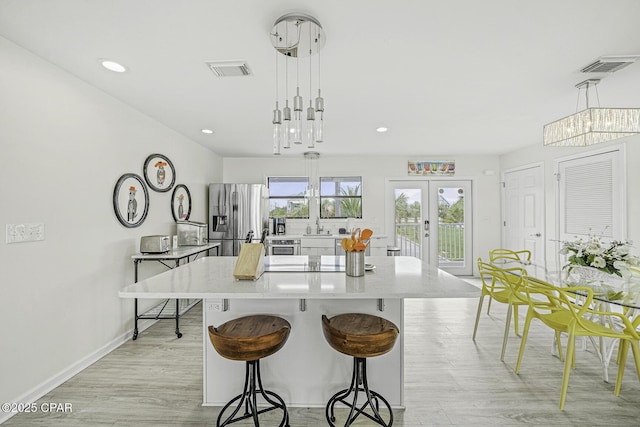 7124 Leeward St, Port St Joe, FL 32456 - kitchen with stainless steel fridge with ice dispenser, a kitchen breakfast bar, a center island, baseboards, and light wood-style flooring