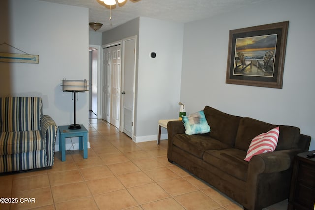 living room with a textured ceiling, baseboards, and light tile patterned floors