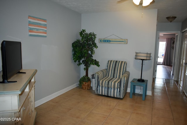 living area featuring a ceiling fan, baseboards, and light tile patterned floors