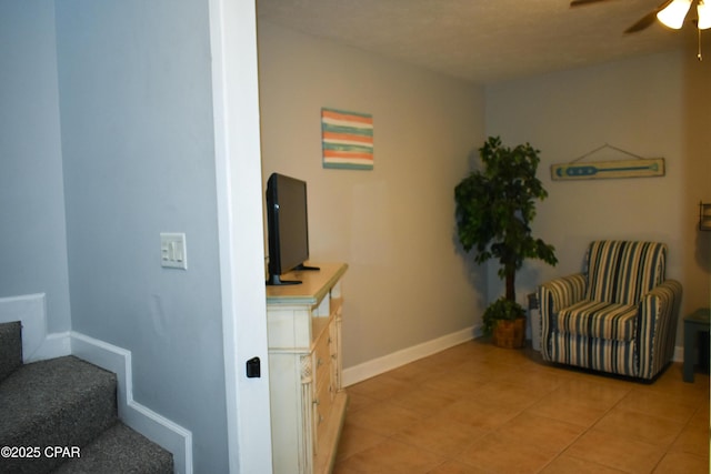 sitting room with light tile patterned floors, baseboards, stairway, and ceiling fan