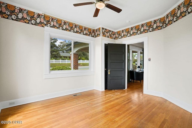 empty room with a ceiling fan, visible vents, baseboards, and light wood-type flooring