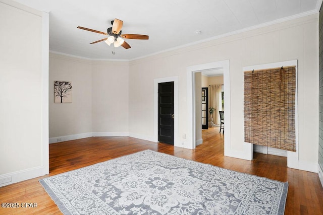 spare room featuring baseboards, crown molding, ceiling fan, and hardwood / wood-style flooring