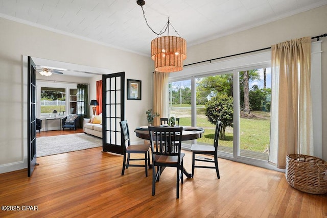 dining area with light wood-style flooring, crown molding, baseboards, french doors, and a notable chandelier