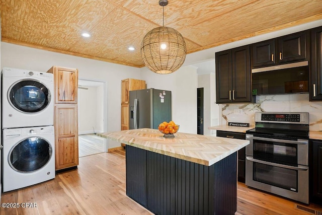 kitchen with stacked washer and clothes dryer, stainless steel appliances, light wood-style floors, and butcher block counters