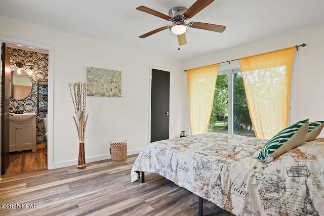 bedroom with connected bathroom, a sink, wood finished floors, baseboards, and ceiling fan