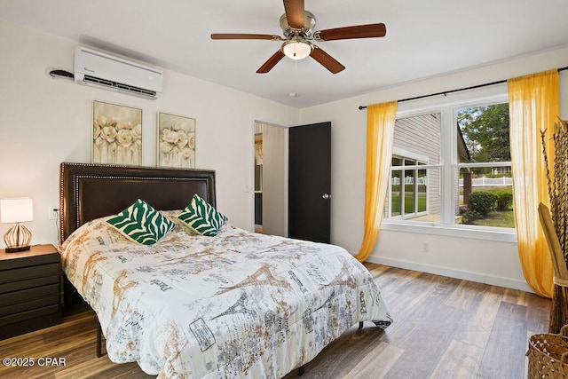 bedroom with a wall mounted air conditioner, baseboards, ceiling fan, and wood finished floors