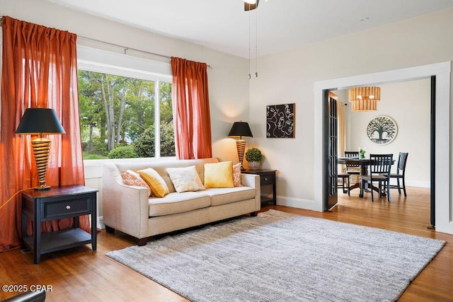 living area with baseboards, wood finished floors, and an inviting chandelier