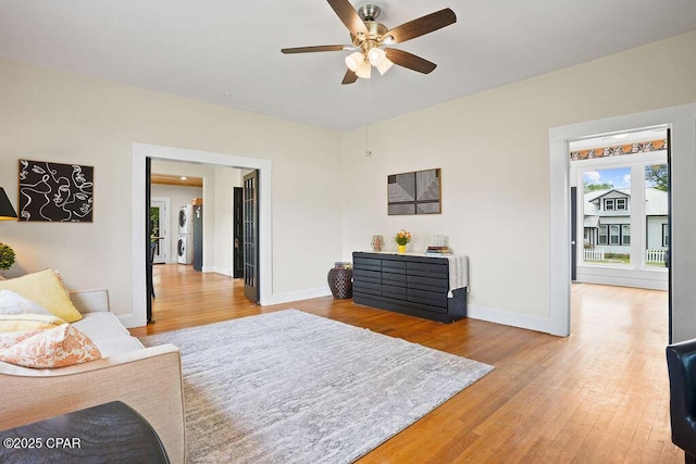 living area with baseboards, wood finished floors, and ceiling fan
