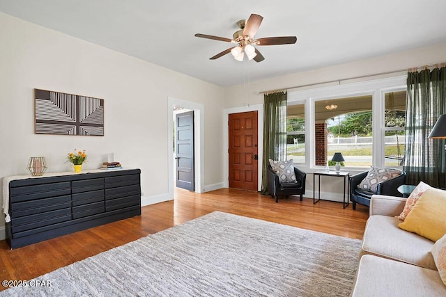 living area featuring baseboards, ceiling fan, and wood finished floors