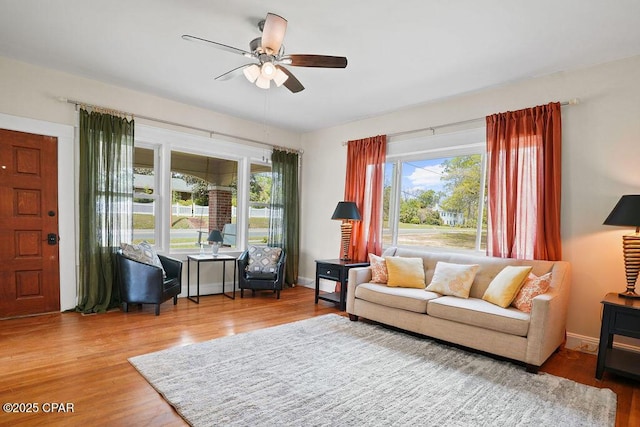 living area with ceiling fan, wood finished floors, and plenty of natural light