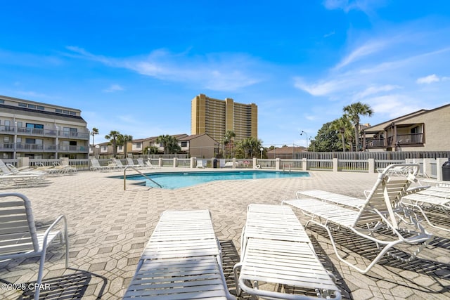 community pool with a patio area and fence