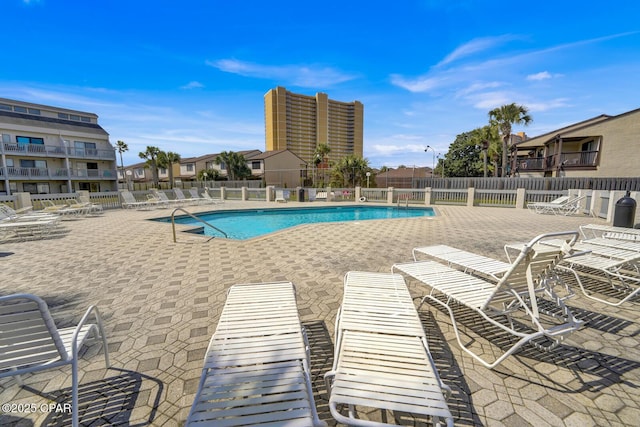 community pool with a patio area and fence